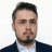 Professional headshot of Sebastian Tschöpel, a friendly and approachable individual with a warm smile. He is dressed in smart business attire, looking directly at the camera with a confident yet welcoming expression.
